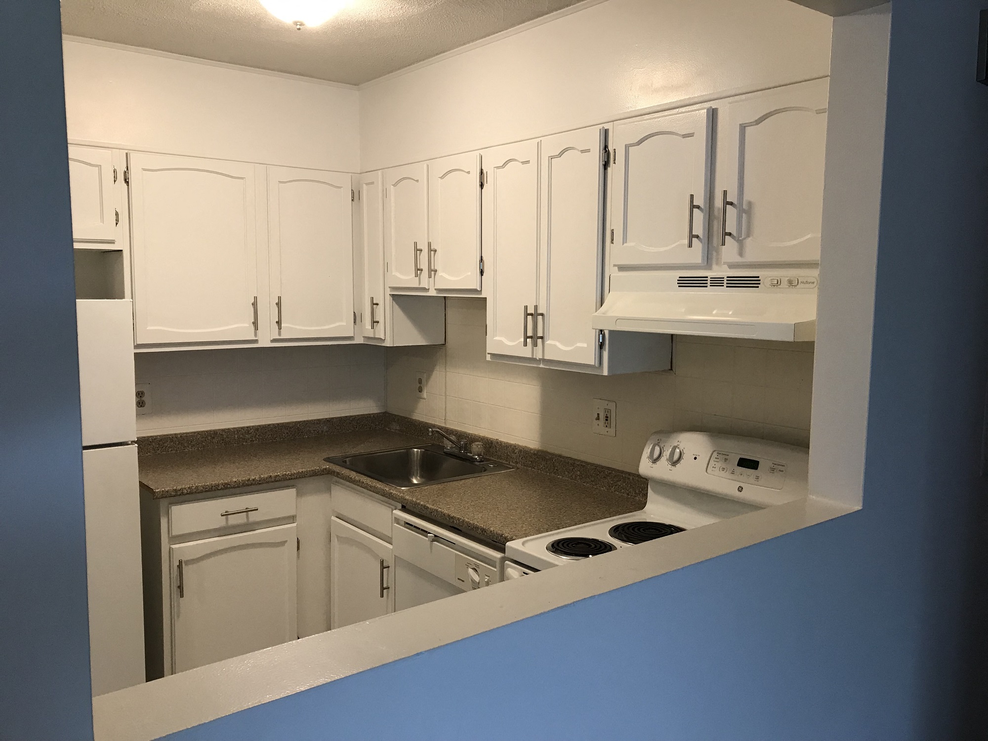 a kitchen with white cabinets and a sink and a stove